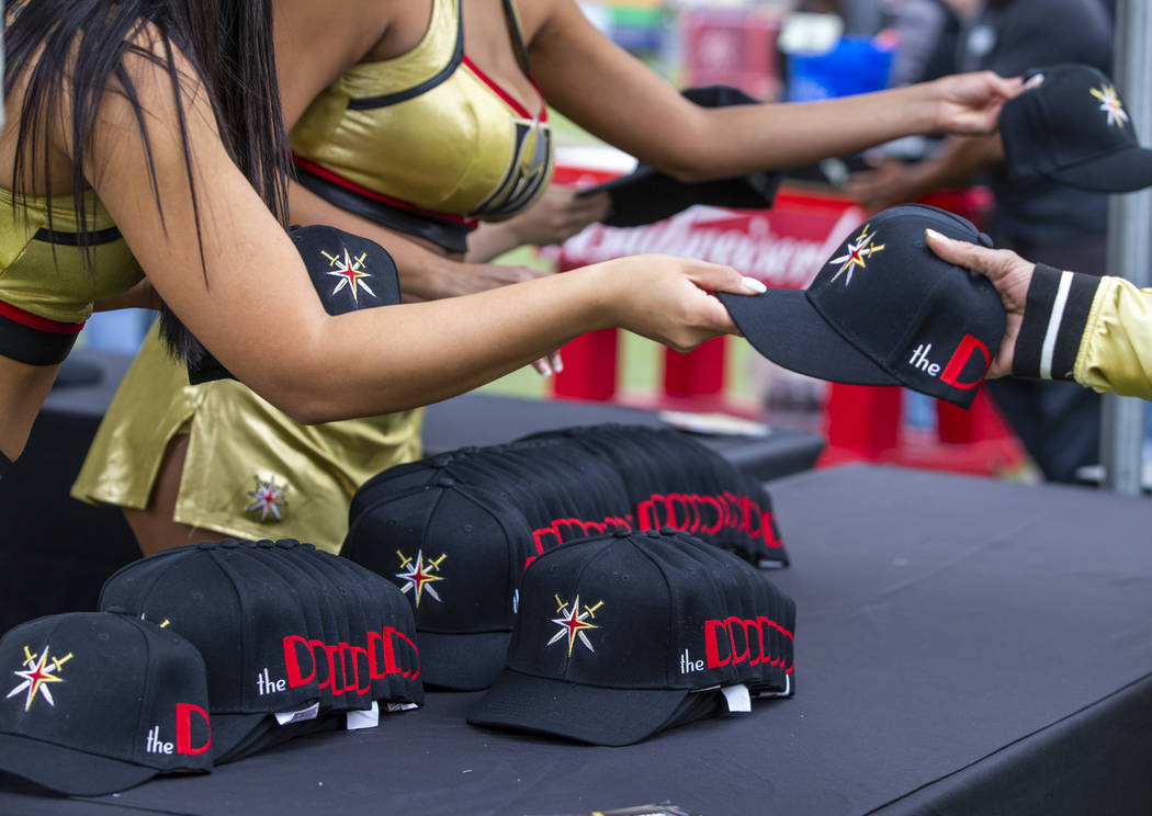 Golden Aces pass out free hats to attendees during the Vegas Golden Knights Fan Fest at the Dow ...