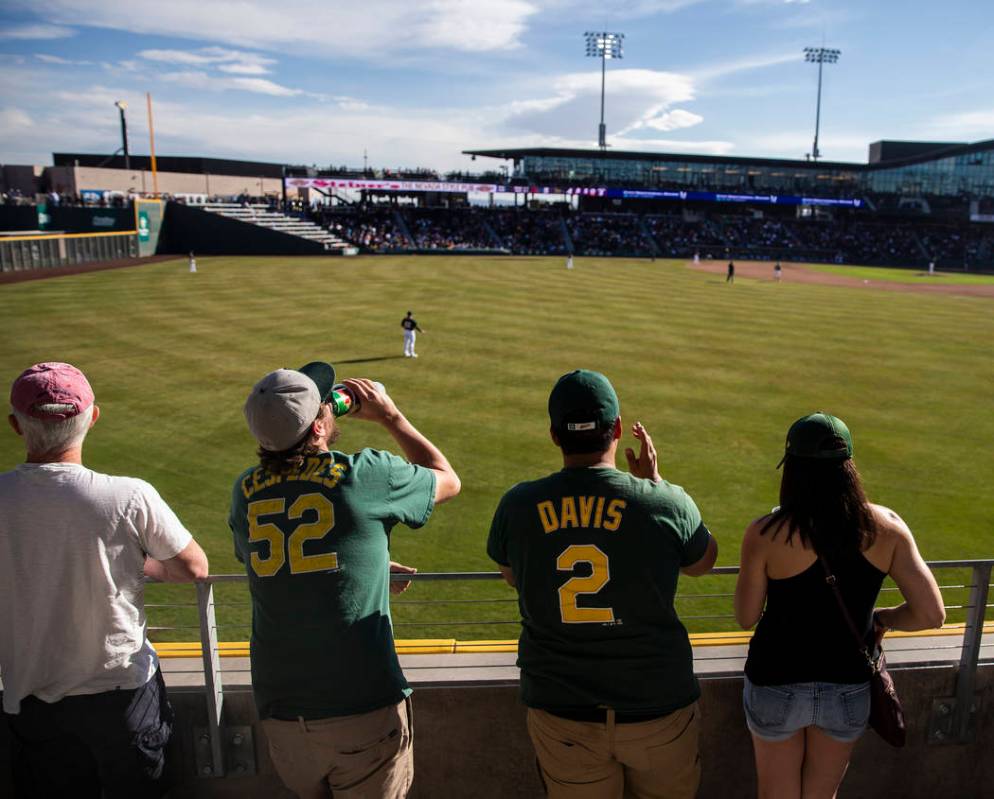 Fans watch the Cleveland Indians play the Oakland Athletics behind the center field fence durin ...