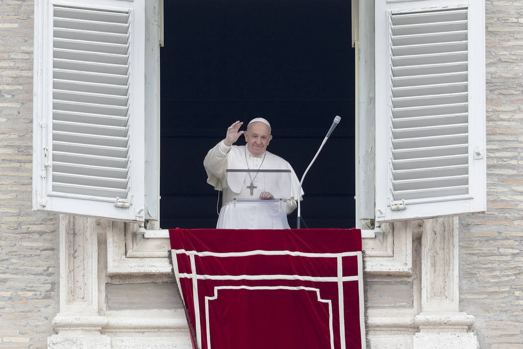 Pope Francis delivers his blessing as he recites the Angelus noon prayer from the window of his ...