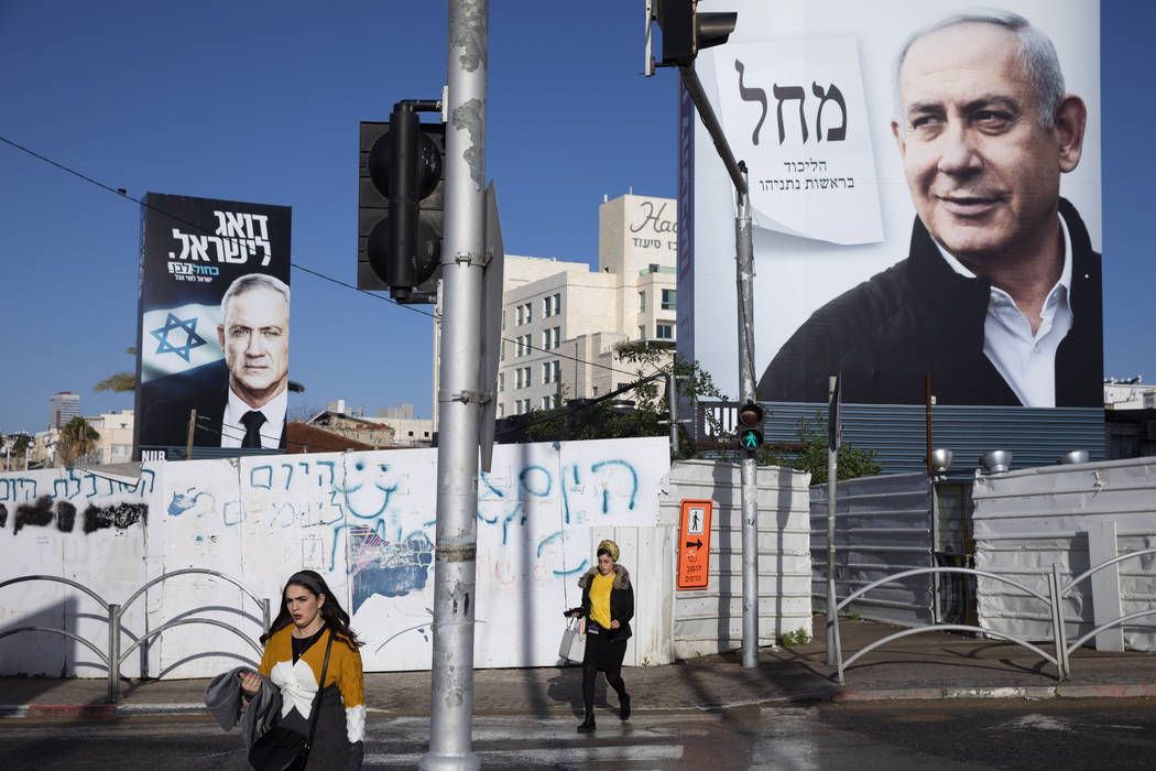 People walk next to election campaign billboards for Likud Party, shows Israeli Prime Minister ...