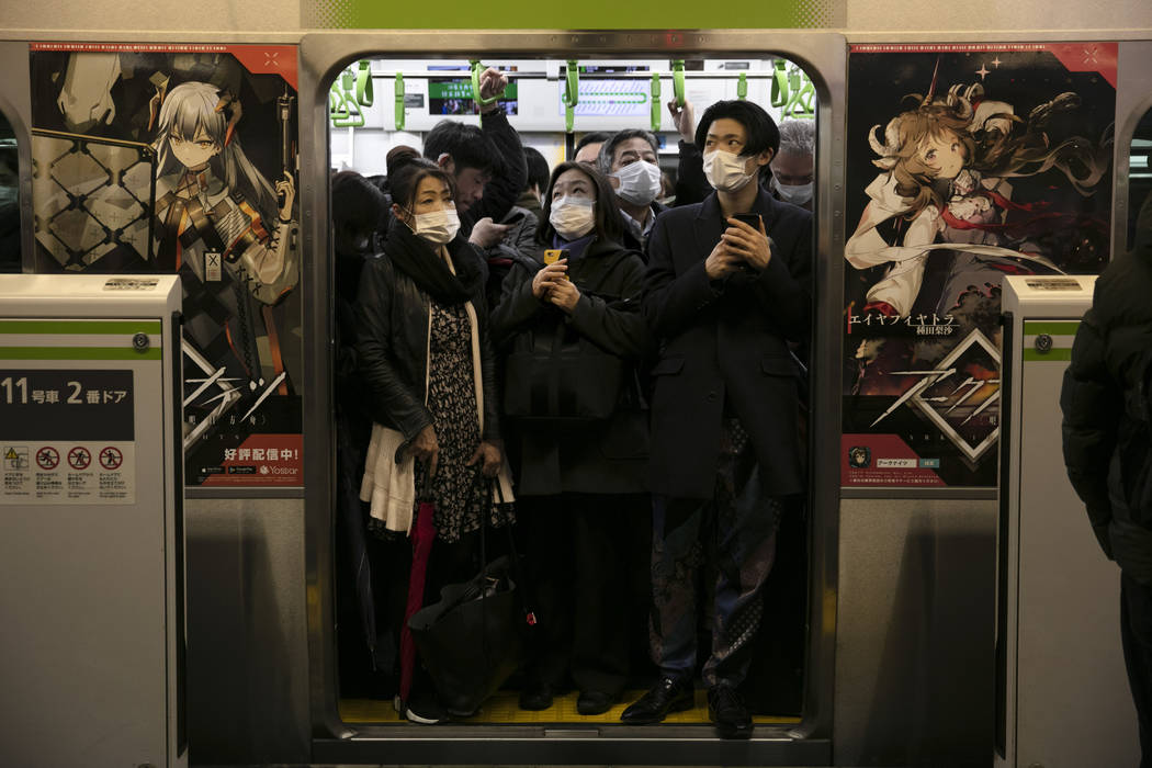 Commuters wearing masks stand in a packed train at the Shinagawa Station in Tokyo, Monday, Marc ...