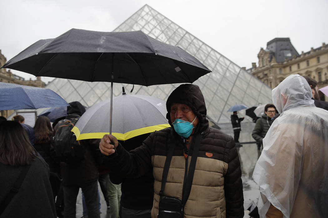 A tourist wearing a mask walks away from the Louvre museum in Paris, Monday, March 2, 2020. The ...