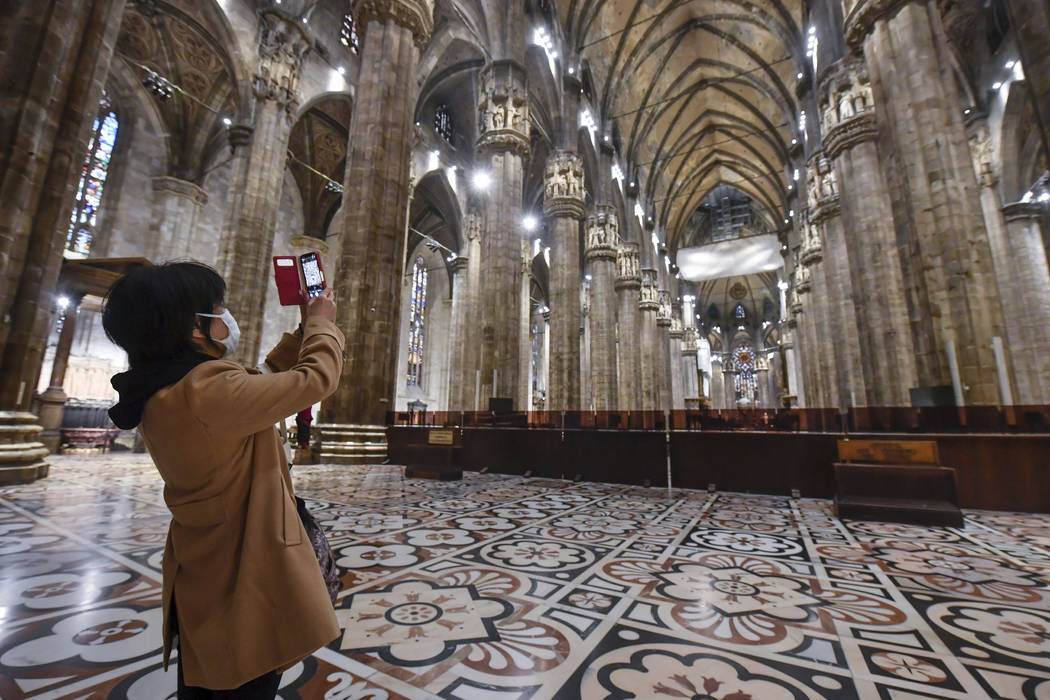 A tourist wearing a face mask takes pictures inside the Duomo gothic cathedral as it reopened t ...
