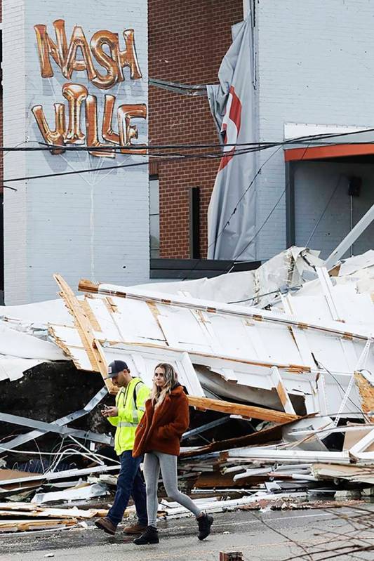 People walk past storm debris following a deadly tornado, Tuesday, March 3, 2020, in Nashville, ...