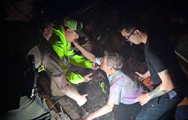 Bill Wallace reaches out to rescue workers who freed him from his home that collapsed on him an ...