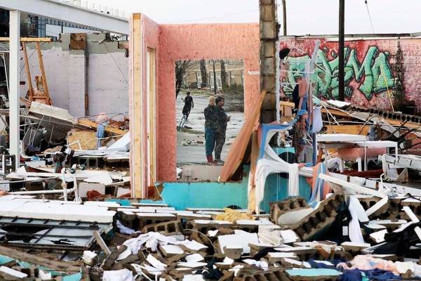 People are reflected in a mirror of a building destroyed by storms Tuesday, March 3, 2020, in N ...