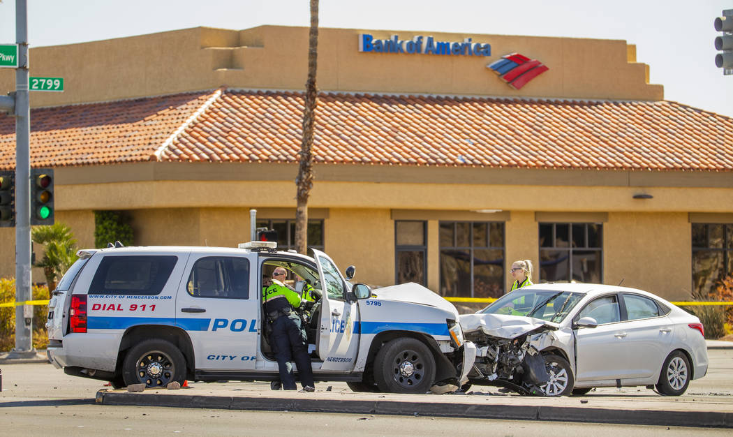 An investigations team works the accident scene where a Henderson Police vehicle was struck whi ...