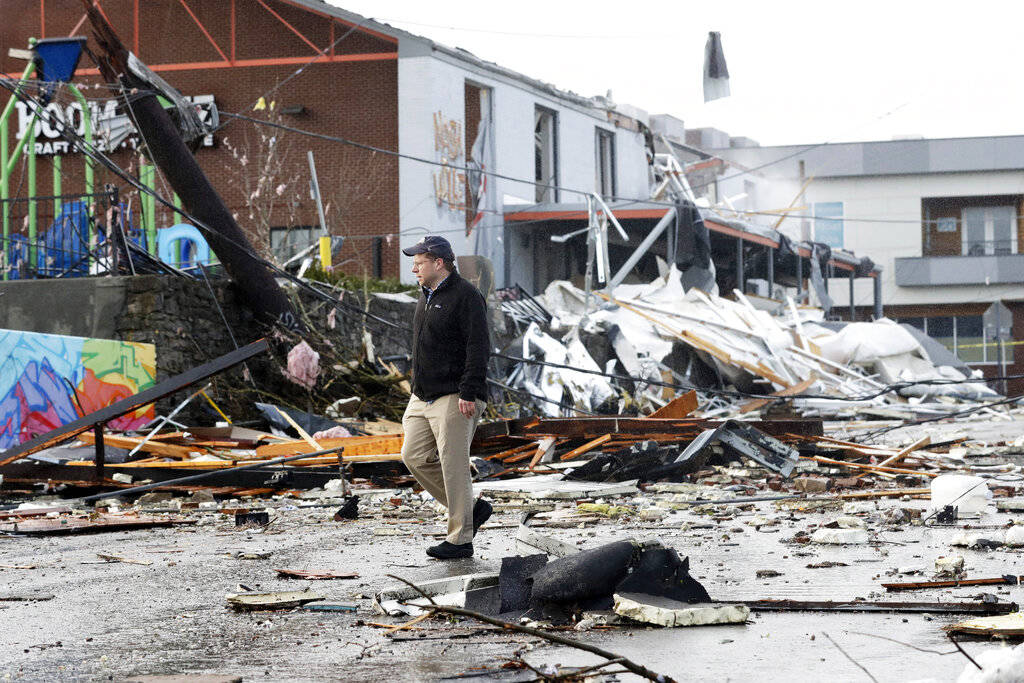 A man walks past storm debris following a deadly tornado Tuesday, March 3, 2020, in Nashville, ...