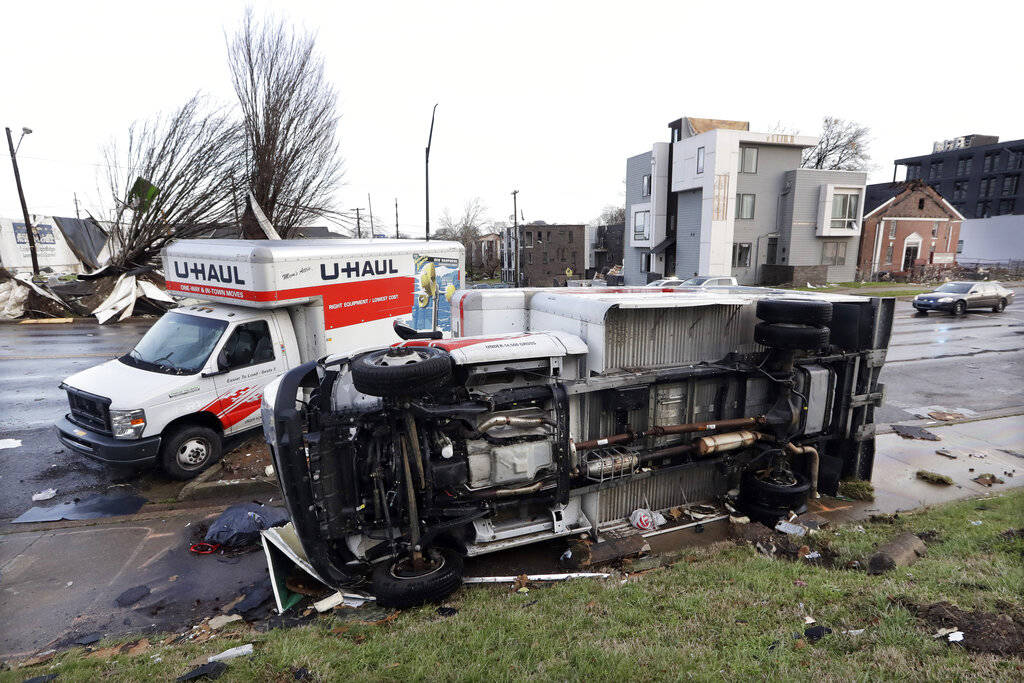 Damaged trucks sit on a sidewalk as well as the street following a deadly tornado, Tuesday, Mar ...