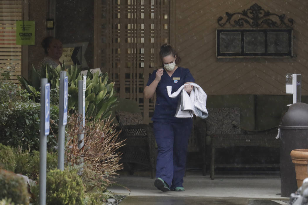 A worker at the Life Care Center in Kirkland, Wash., near Seattle, wears a mask as she leaves t ...