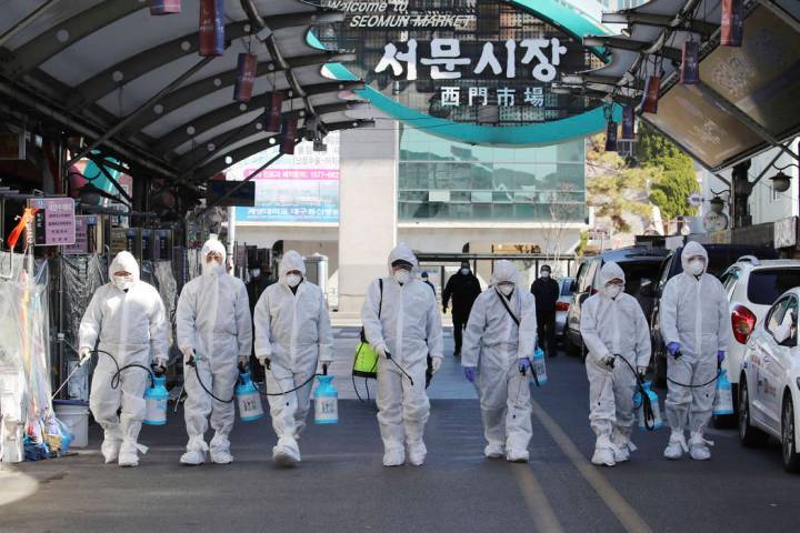 Workers wearing protective gears spray disinfectant as a precaution against the COVID-19 at a l ...