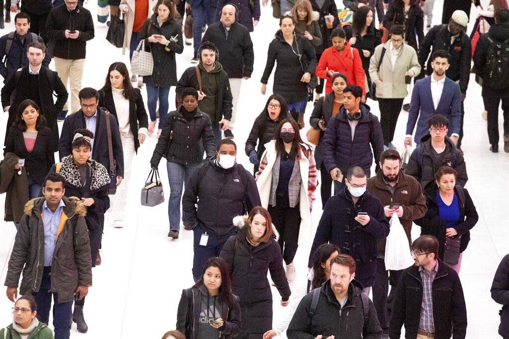 Three commuters, center, wear masks as they walk through the World Trade Center transportation ...