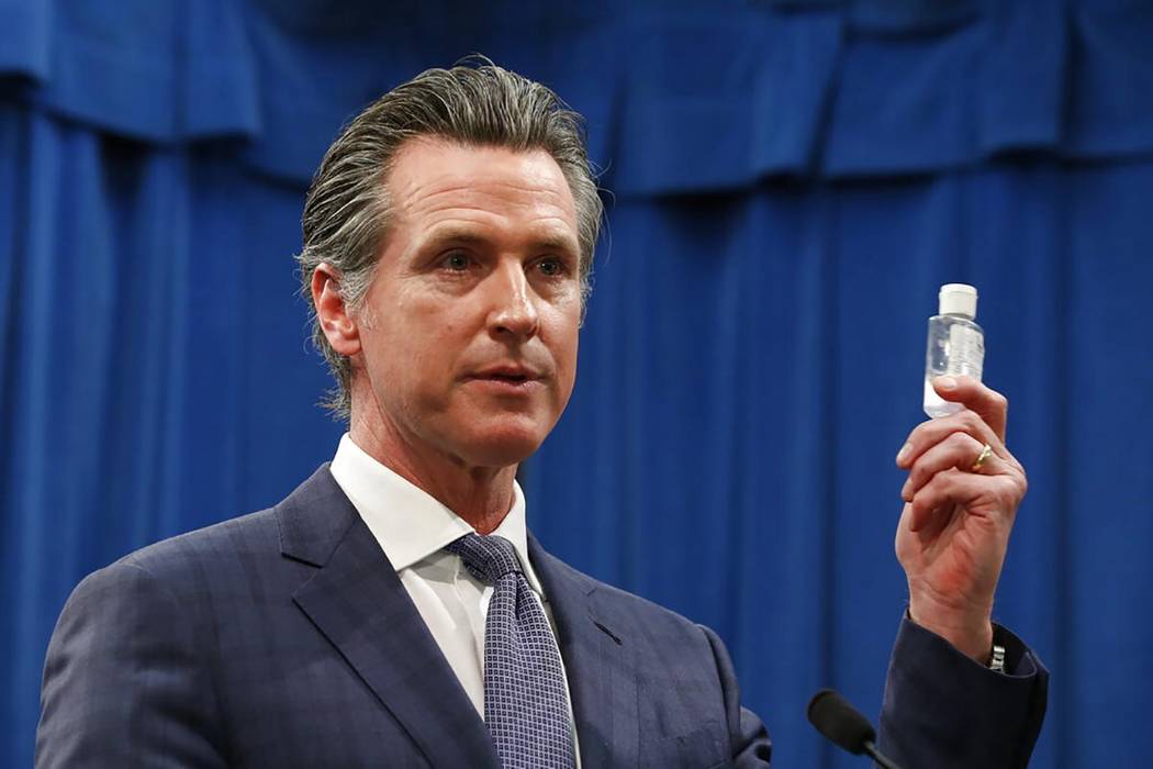 California Gov. Gavin Newsom displays a bottle of hand sanitizer while saying the state would t ...