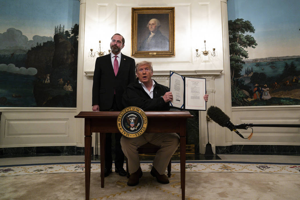 Secretary of Health and Human Services Alex Azar looks on as President Donald Trump shows a spe ...