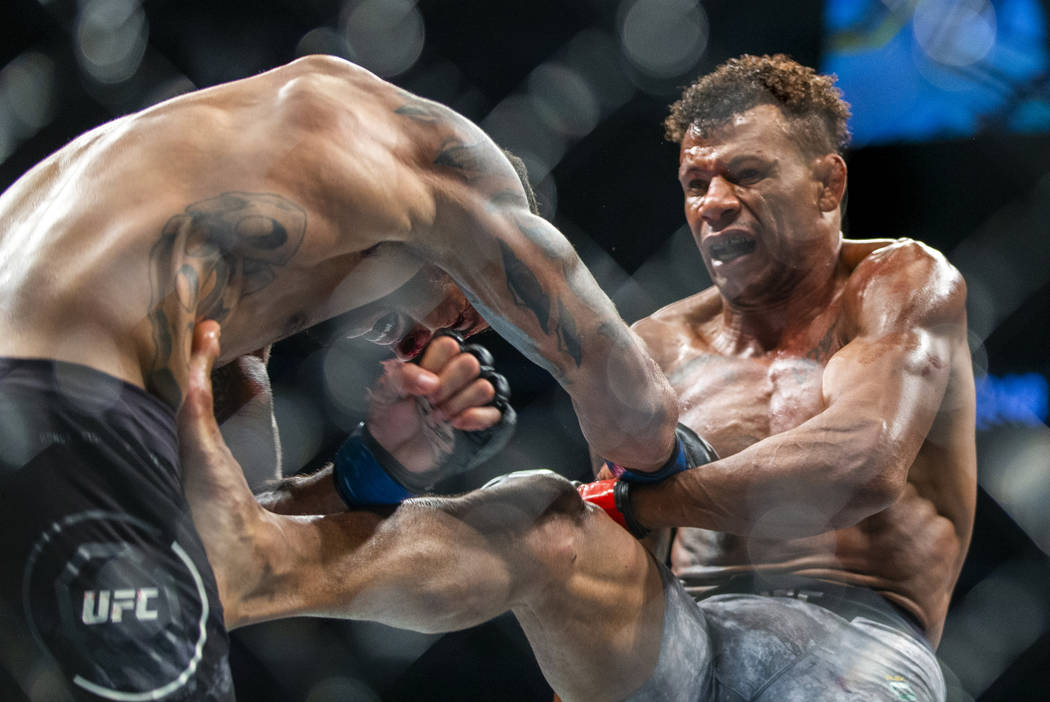 Welterweight Max Griffin, left, takes a kick to the stomach from Alex Oliveira during the third ...