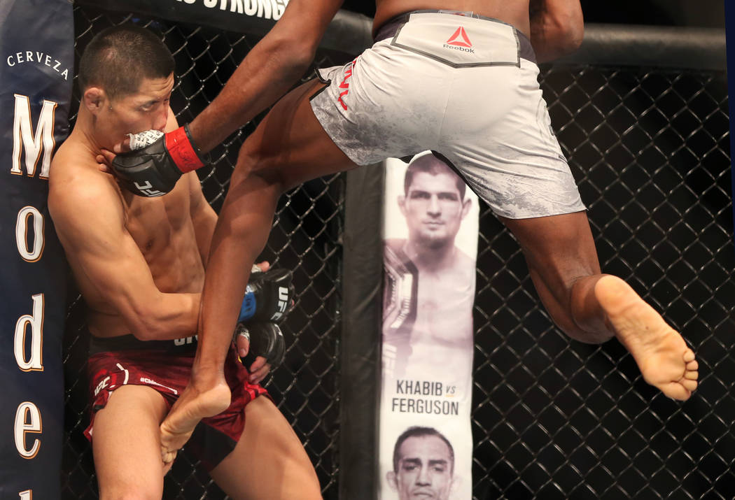 Welterweight Li Jingliang, left, takes a kick and punch from Neil Magny during the first round ...