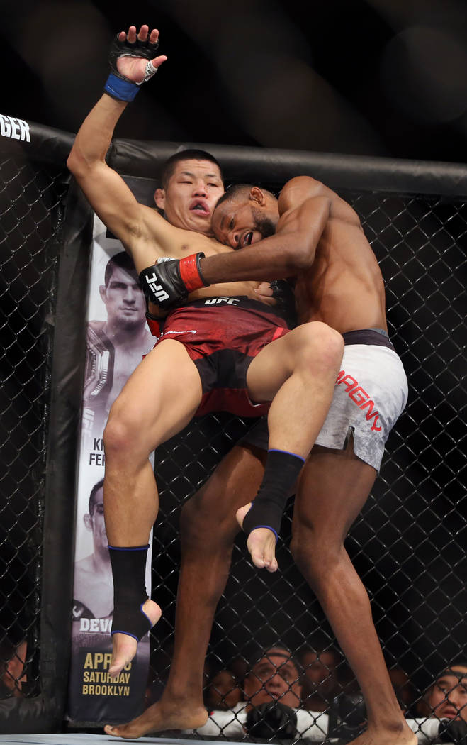 Welterweight Li Jingliang, left, is lifted off his feet by Neil Magny during the second round o ...