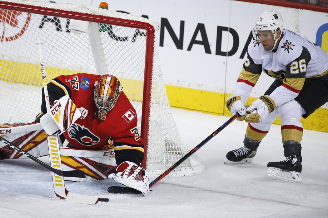 Vegas Golden Knights' Nick Cousins, left, gets past Calgary Flames' Rasmus Andersson during fir ...