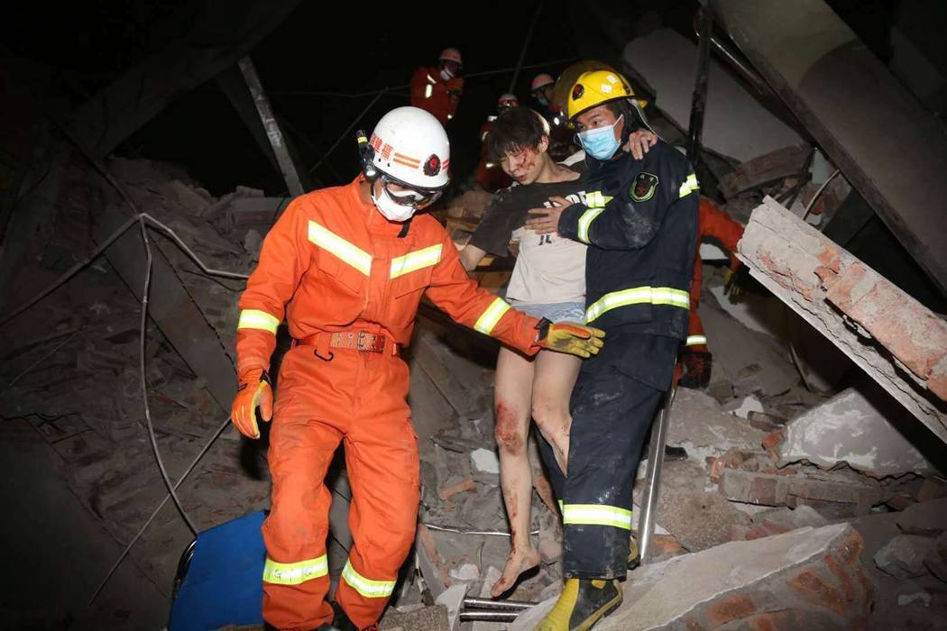 Rescuers help a woman from the rubble of a collapsed hotel building in Quanzhou city in southea ...