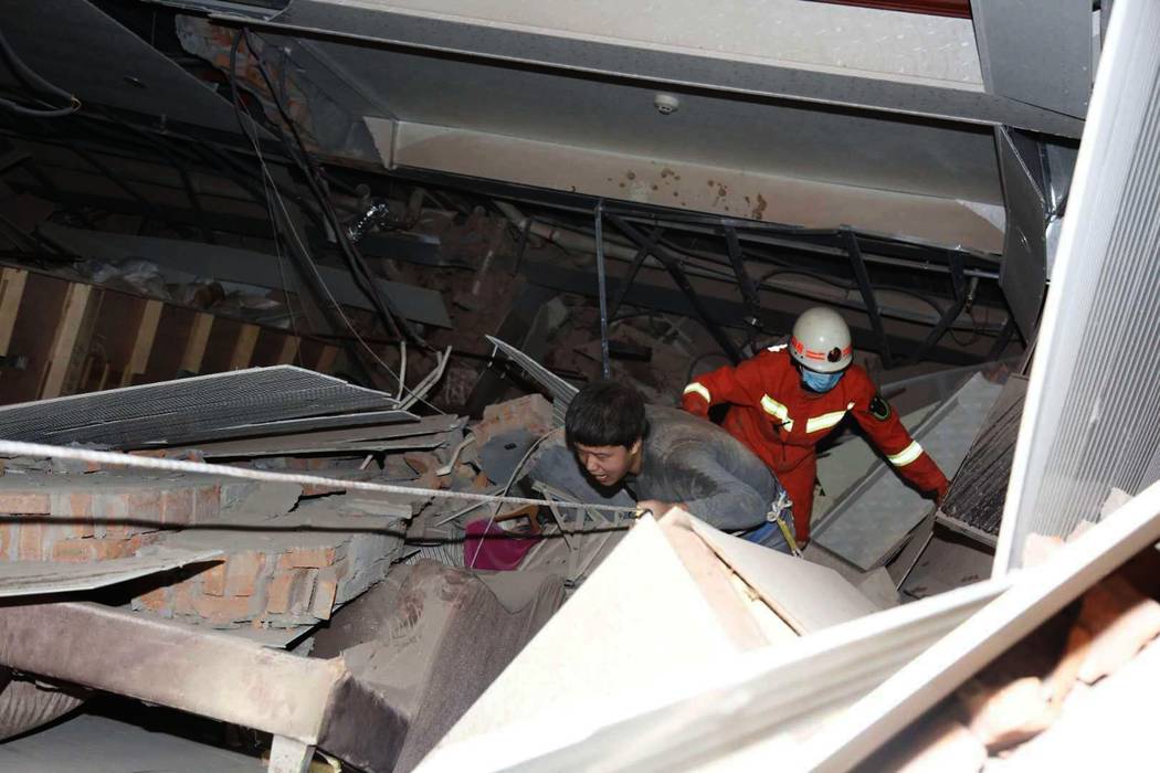 A man is assisted out from the rubble of a collapsed hotel building in Quanzhou city in southea ...