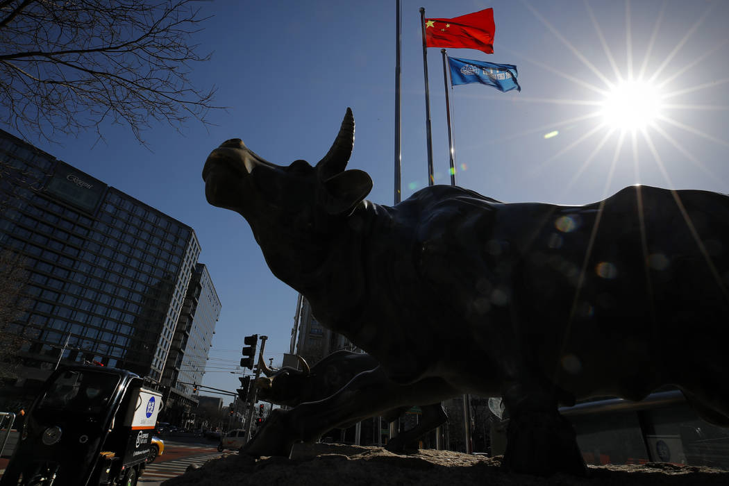 A delivery worker ride his cart passes by the investment icon bull statue on display outside a ...
