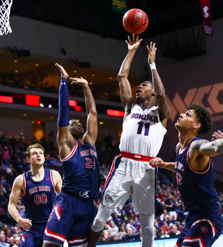 Gonzaga Bulldogs' Joel Ayayi (11) shoots between St. Mary's Gaels' Malik Fitts (24) and Dan Fot ...