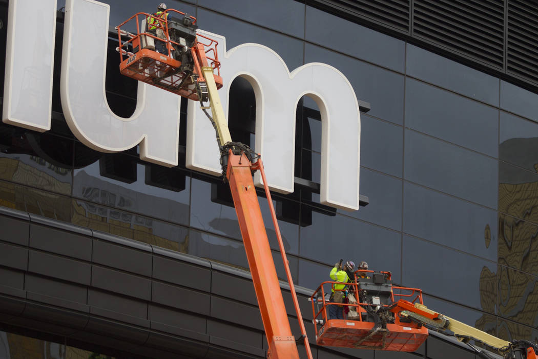 A worker takes a photo after helping install the last letter in the signage for the Raiders All ...