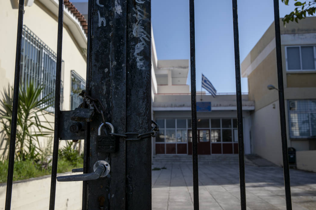 A Greek flag flies on the roof of a closed school in a suburb of Athens, Wednesday, March 11, 2 ...