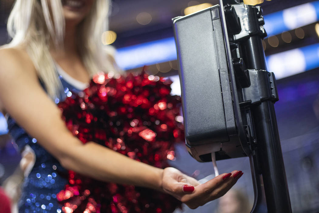A University of Arizona cheerleader uses hand sanitizer after the game against University of Wa ...