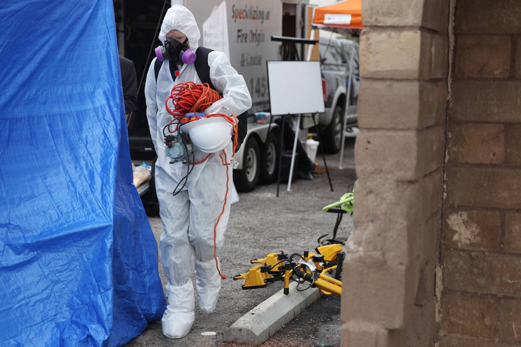 An employee with the Forensic Investigations Group carries equipment into the Alpine Motel duri ...