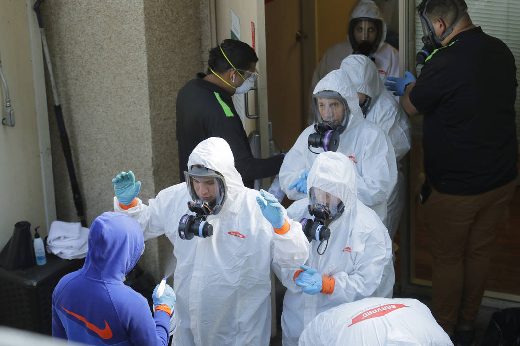 Servpro cleaning workers are sprayed as they exit the Life Care Center in Kirkland, Wash., Thur ...