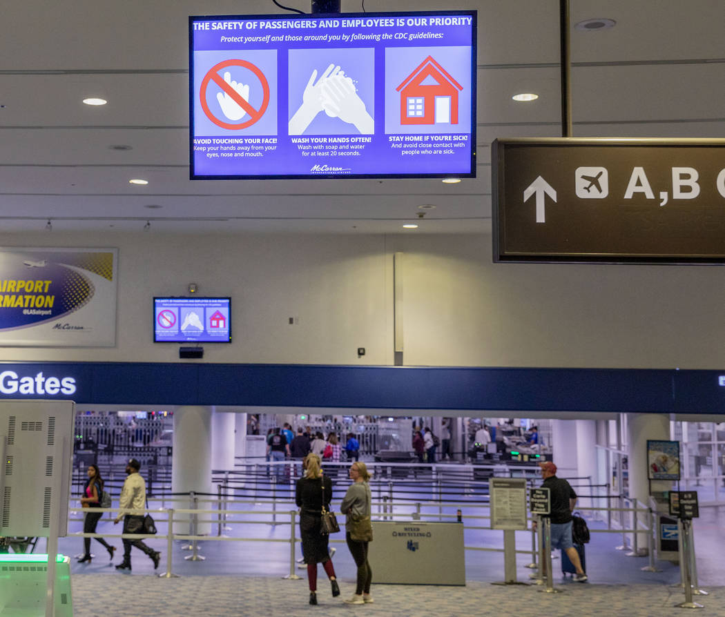 A slide flashes on screens reminding passengers to wash hands often, at the McCarran Internatio ...