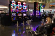 A passenger wearing a mask, right, sits about one of the near empty slot machine areas in Conco ...