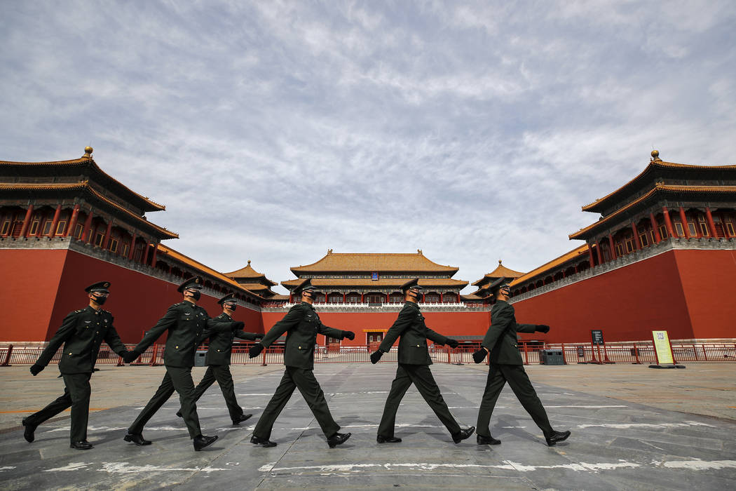 Soldiers wearing protective face masks march past the closed entrance gates to the Forbidden Ci ...