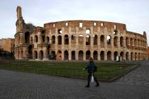 A woman walks in front of Rome's ancient Colosseum in the afternoon of Thursday, March 12, 2020 ...