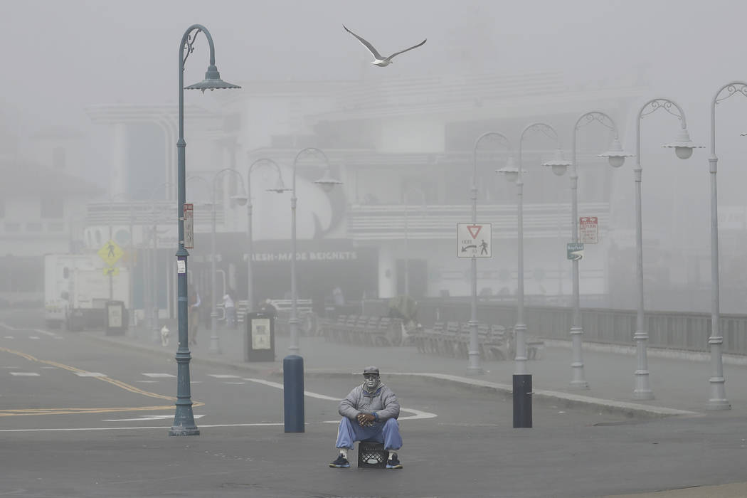 A street performer sits alone at Fisherman's Wharf in San Francisco, Thursday, March 12, 2020. ...
