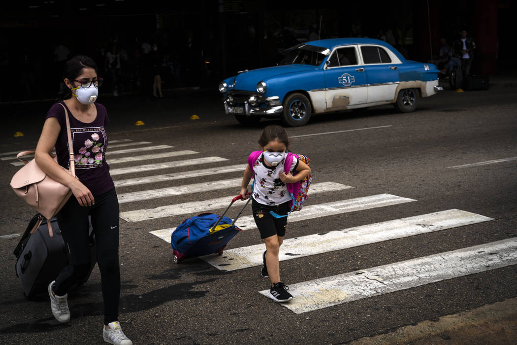 Tourists, wearing mask as a precaution against the spread of the new coronavirus, cross the str ...