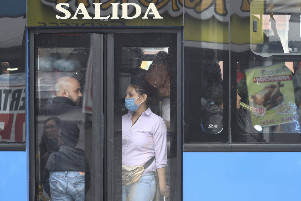 A woman on a public transportation bus a wears a surgical mask in Quito, Ecuador, Thursday, Mar ...