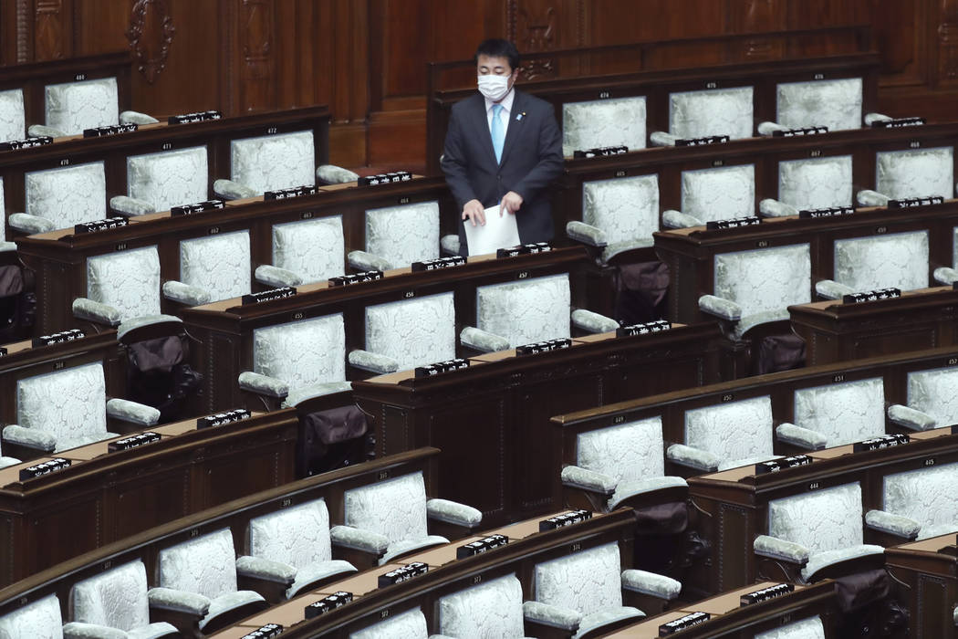 A lawmaker wearing face mask arrives for a plenary session at the Lower House in Tokyo, Thursda ...