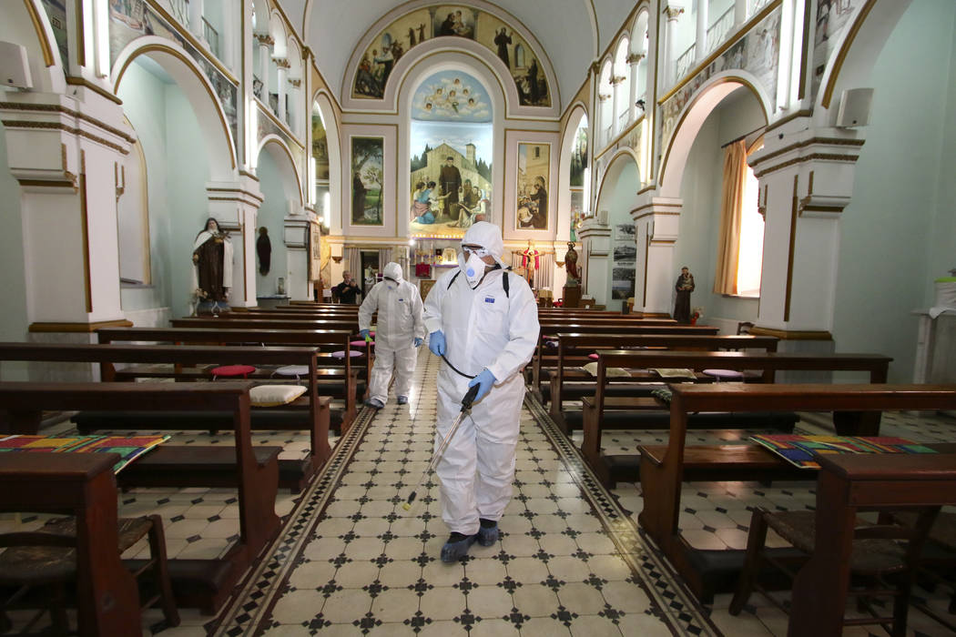 Workers wearing protective clothing disinfect St Antonio Church, in Bayrakli district of Izmir, ...