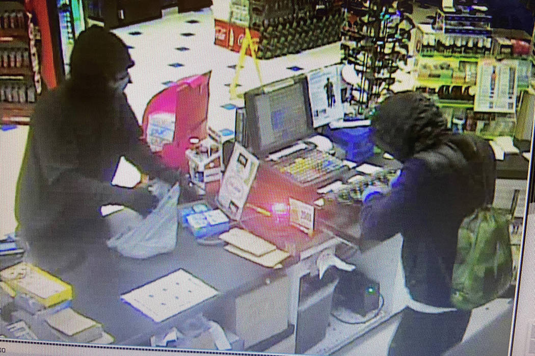A still from video surveillance shows two men armed with AK47-like assault rifles stealing cash ...