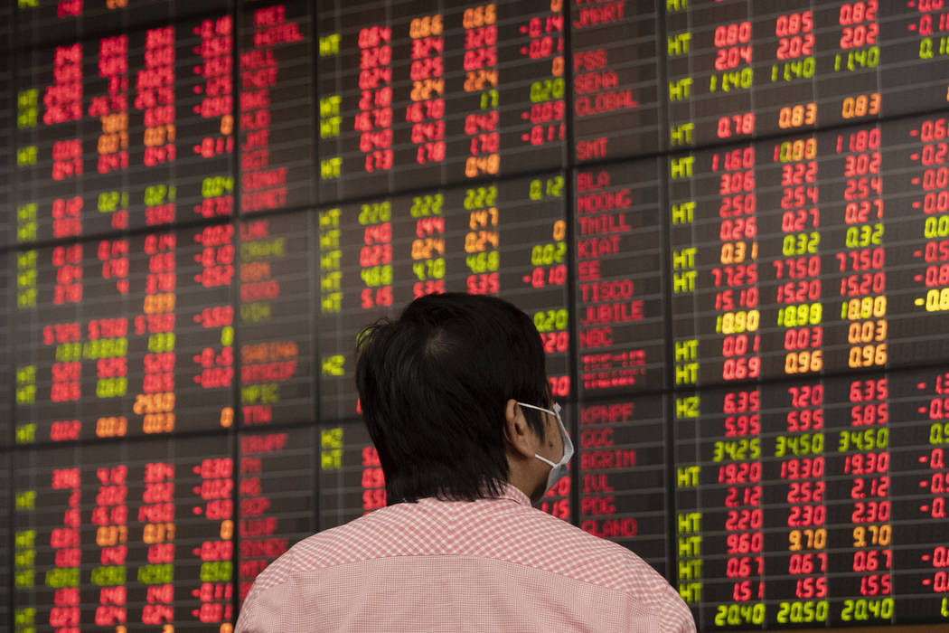 A Thai investor checks an electronic board showing stock prices at Asia Plus Securities, a priv ...