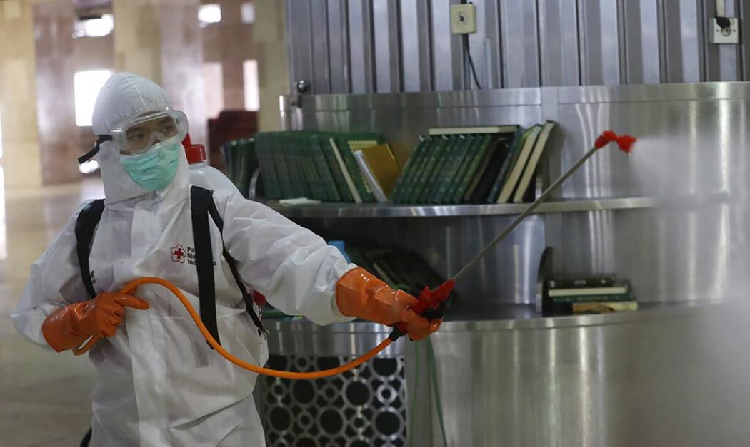 An official sprays disinfectant in the wake of the new coronavirus outbreak at Istiglal mosque ...