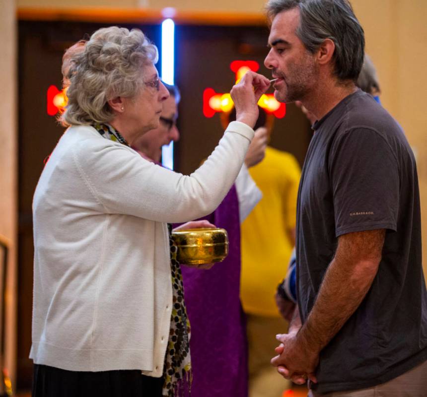 Janet O'Donnell, left, gives the holy sacrament to another parishioner during Sunday Mass at St ...