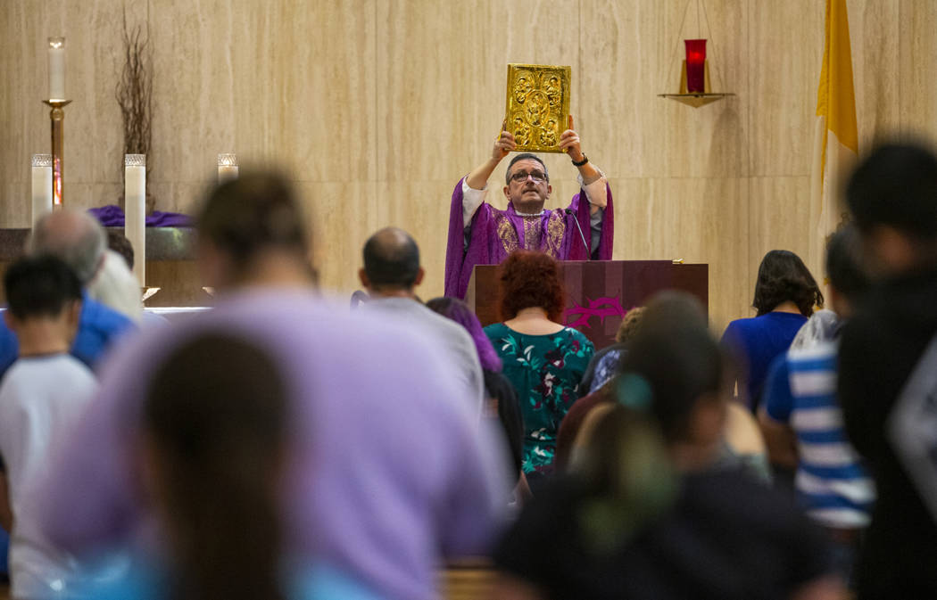Monsignor Gordon raises up the Bible during Sunday Mass at St. Anne's Catholic Church where par ...