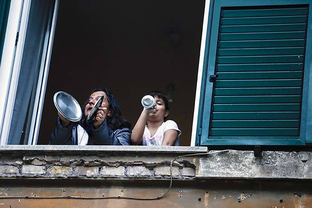 A woman and a girl play pots from the window of they home during a flash mob launched throughou ...