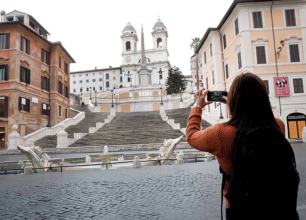 A woman takes photos of The Spanish Steps in Rome Friday, March 13, 2020. A sweeping lockdown i ...