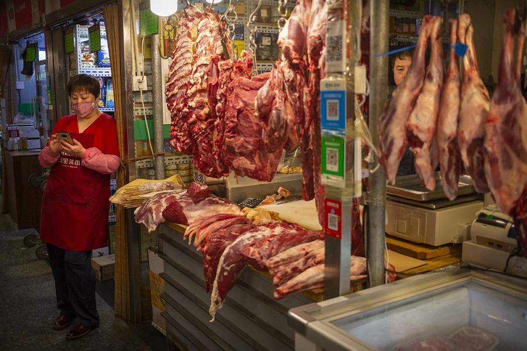 An employee wears a face mask as she waits for customers at a meat stall at a market in Beijing ...