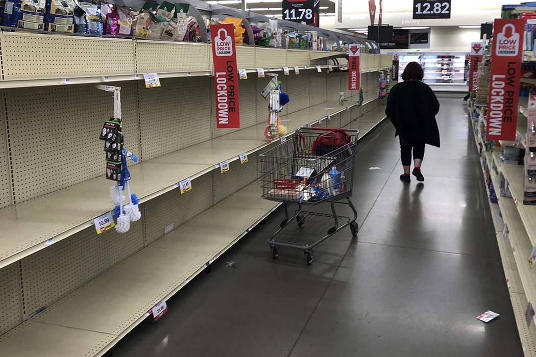 A woman shops among empty shelves at a Hy-Vee food store Friday, March 13, 2020, in Overland Pa ...