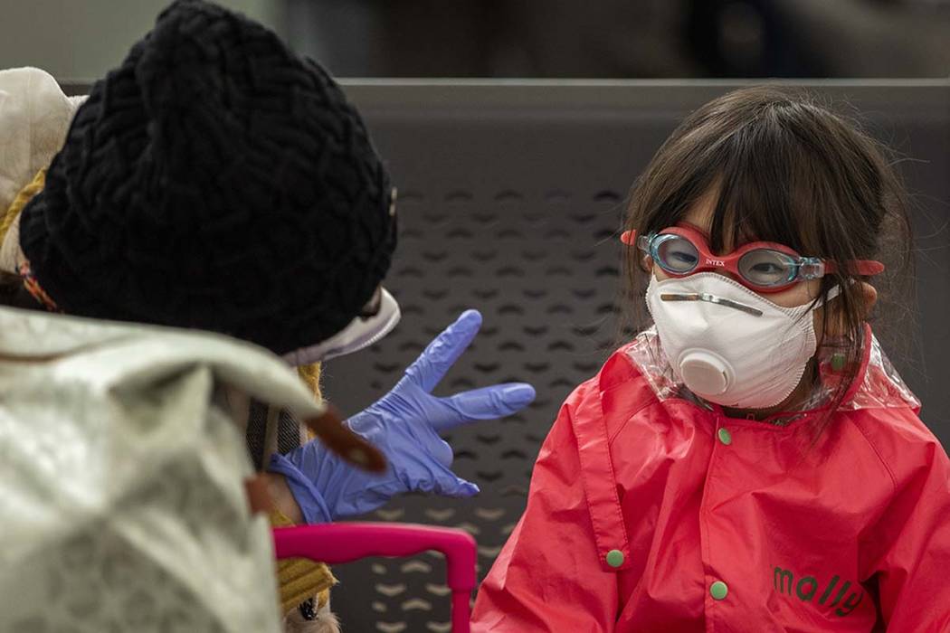 A woman plays with her daughter as they wait at Barcelona airport, Spain, Saturday, March 14, 2 ...